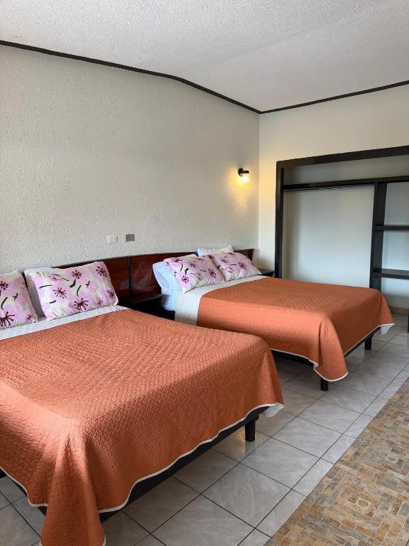 a hotel room with two beds with orange sheets at Hotel Virrey in Reynosa