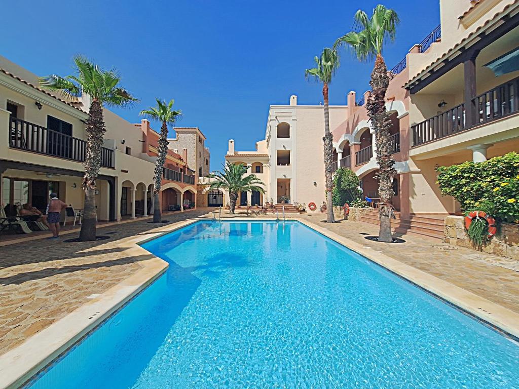 a large blue swimming pool in a courtyard with palm trees at Harbour Lights IV in Villaricos