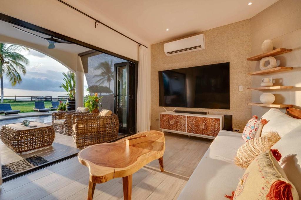 a living room with a tv and a couch and a table at Playa Potrero Beachfront Ocean Views, Pool & BBQ in Santa Cruz