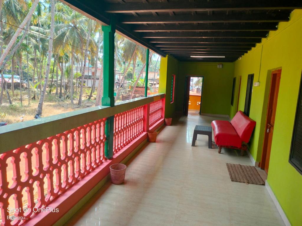 a balcony with a red chair and green walls at Totadamane in murdeshwar in Māvalli