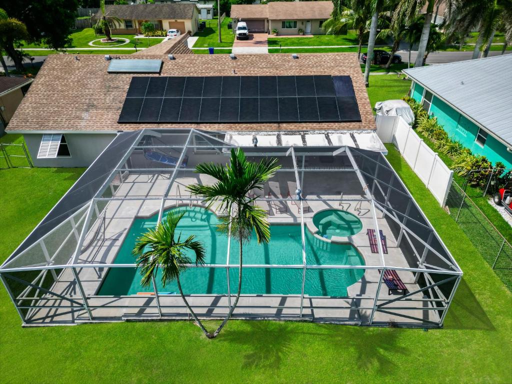 an overhead view of a swimming pool with solar panels on a house at Splash & Relax Games WiFi BBQ Fire Pit Boat Lake in Royal Palm Beach