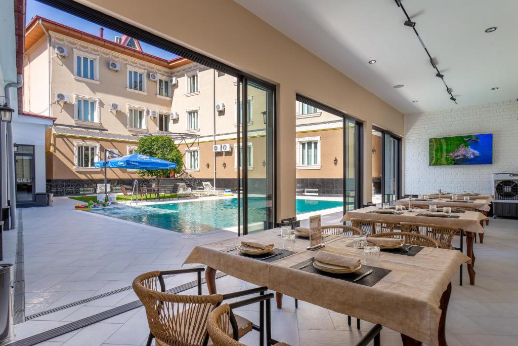 a restaurant with tables and chairs and a swimming pool at Grand Nur Hotel in Tashkent