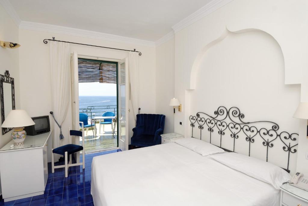 a white bedroom with a bed and a balcony at Hotel Aurora in Amalfi