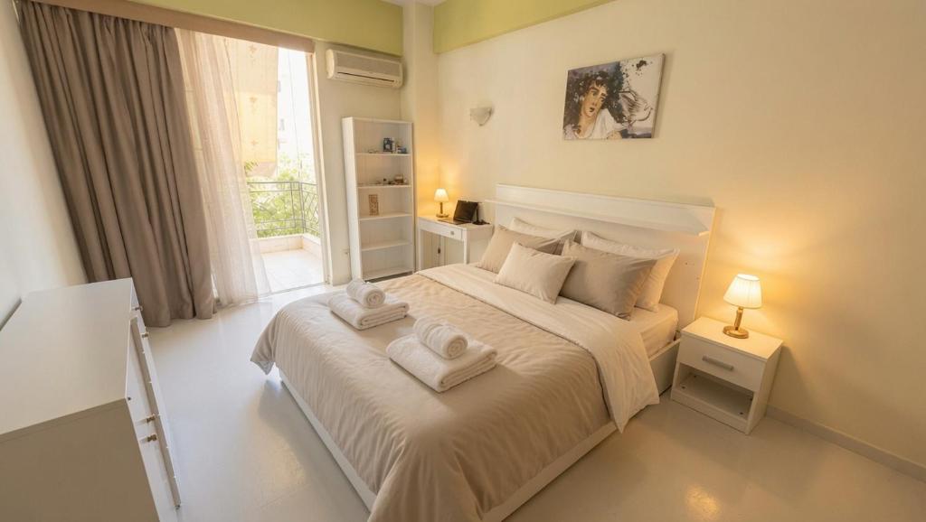 a white bedroom with a bed with towels on it at Kalamata Deluxe Suite By AGGELOS in Kalamata