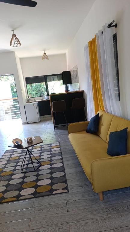 a living room with a yellow couch and a piano at Le Mäysa dzindzano Residence in Sada
