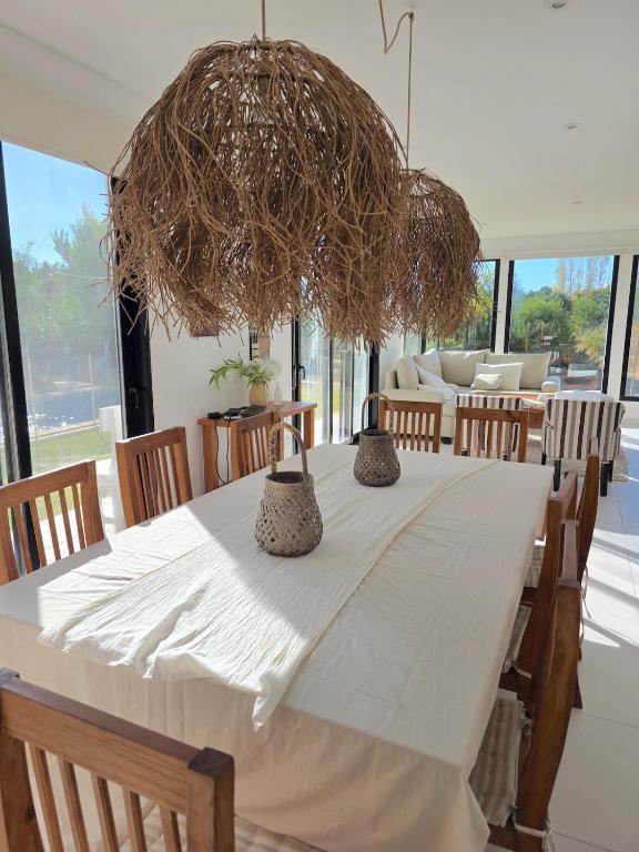 a dining room with a white table and a large chandelier at COSTA ESMERALDA S3 para 10 pileta y jardín privados in Pinamar