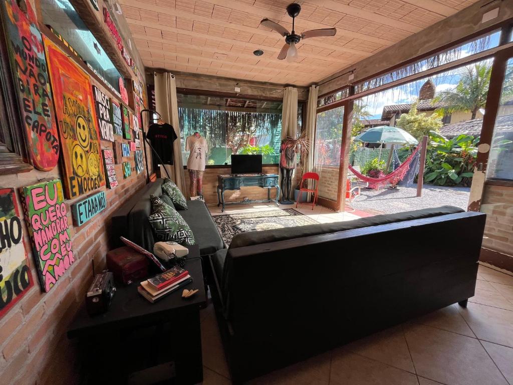 a living room with a black couch and a hammock at Tia Chica Camburi in Camburi