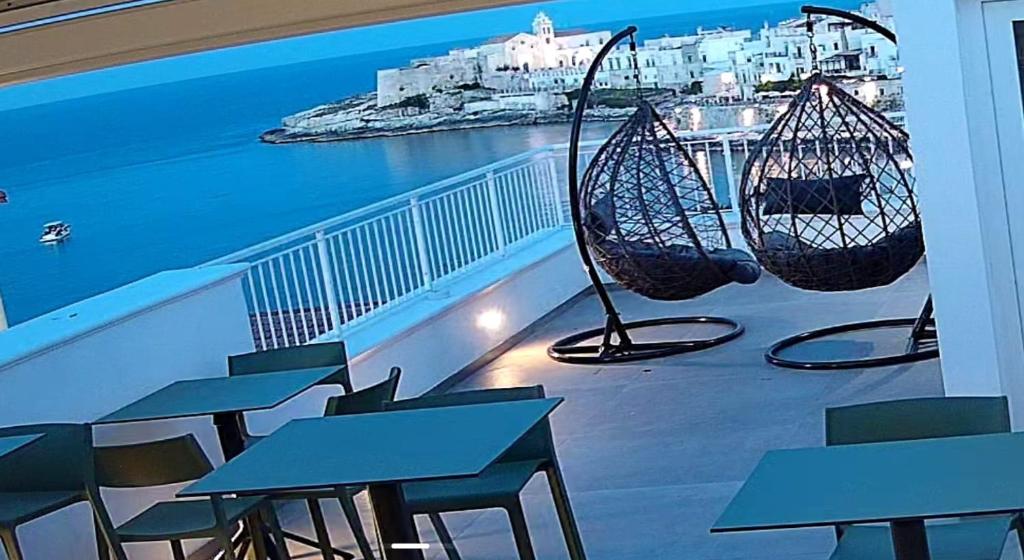 a balcony with tables and chairs and a view of the ocean at my Vesta Suites in Vieste