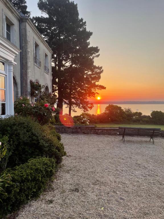 a bench in front of a house with the sunset at Manoir Mer & Pins in Fouesnant