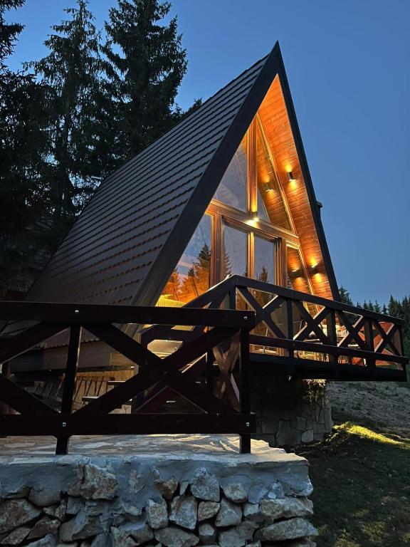 a house with a pitched roof and a stone wall at A-Frame Tadić Tara in Ljuboš