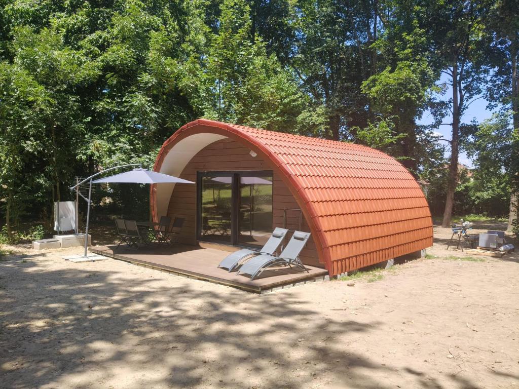 an orange building with two chairs and an umbrella at Ecolodge Insolite in La Bâtie-Montgascon
