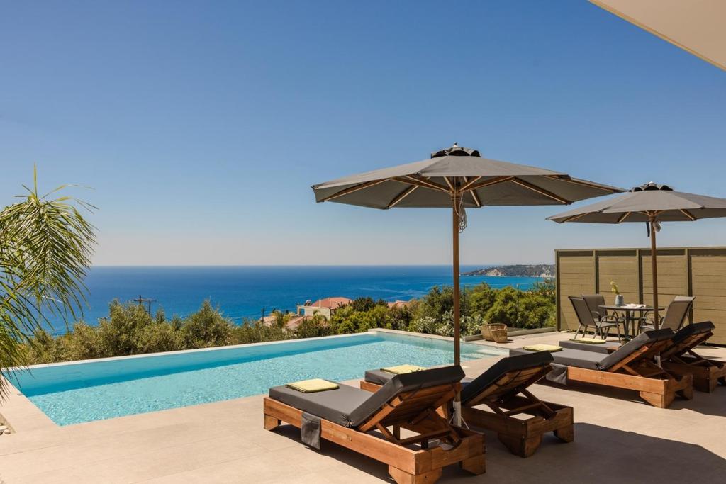 a swimming pool with two umbrellas and two chairs and a swimming poolvisor at Villa George by Villa Select in Lourdata