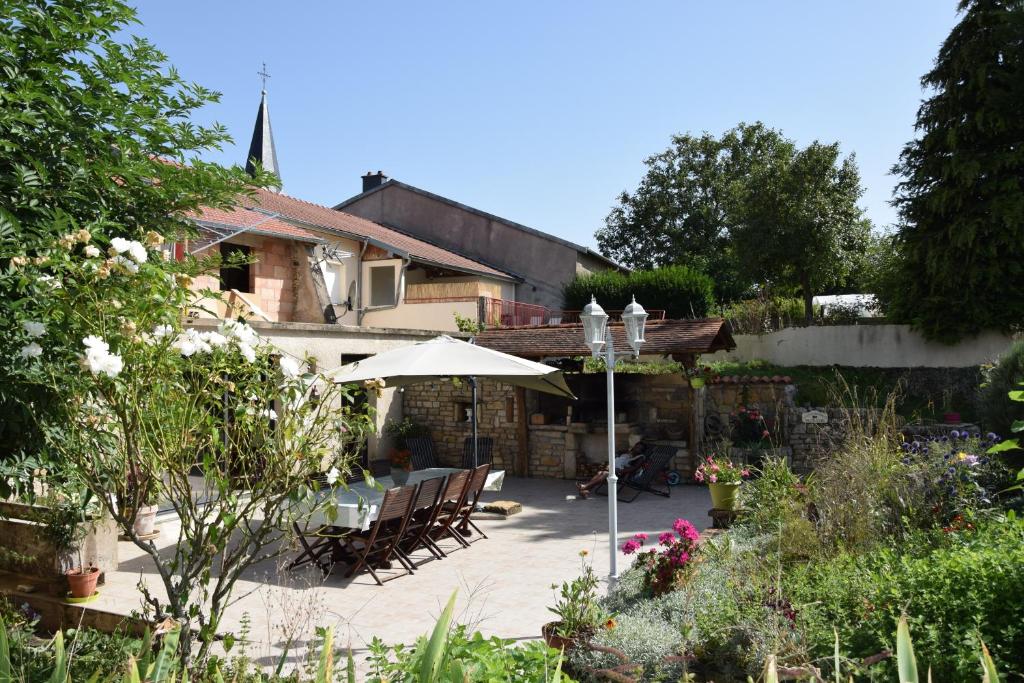 a house with a patio with chairs and an umbrella at Gîte des 3 Suissesses in Saint-Paul