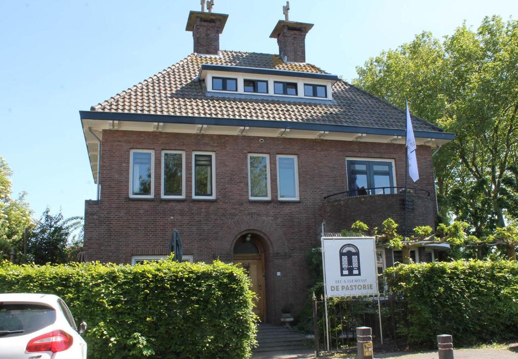 a red brick house with a sign in front of it at B&B de Pastorie Terneuzen in Terneuzen