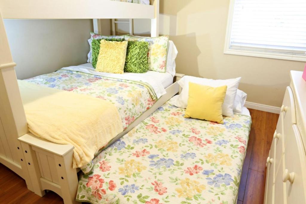 two beds in a small room with yellow and green pillows at Anaheim California, Beautiful Pool Home, Short Walk to Disney in Anaheim