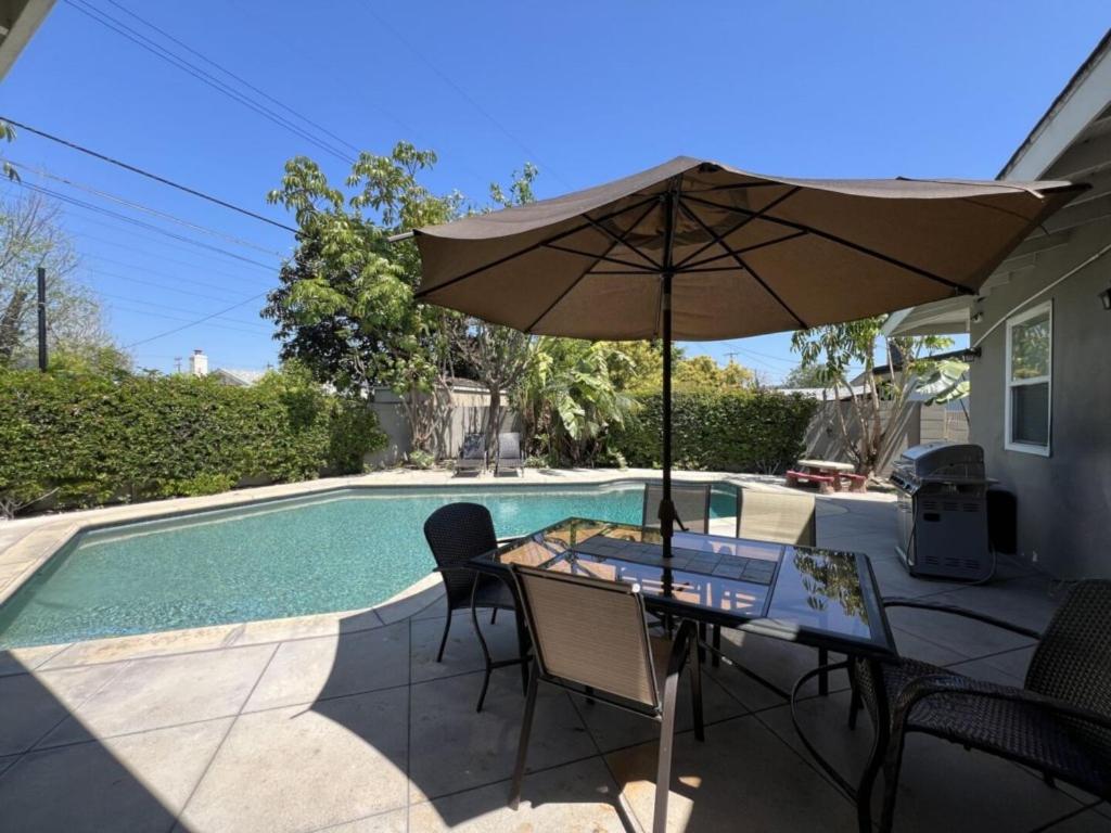 a table with an umbrella next to a swimming pool at Gorgeous Pool Home 1/2 Mile Walk to Disney in Anaheim