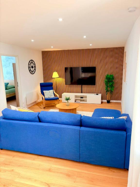 a living room with a blue couch and a tv at Le Salon des Voyageurs - Appartement Climatisé avec Terrasse et Parking Gratuit à Proximité in Dole