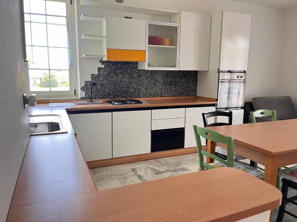 a kitchen with white cabinets and a wooden table at Appartamento Arena by OTIUM in Giulianova