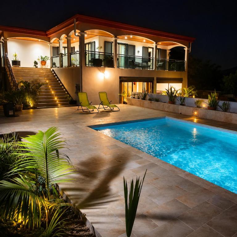a swimming pool in front of a house at night at L'Escapade Volcanique in Sainte-Rose
