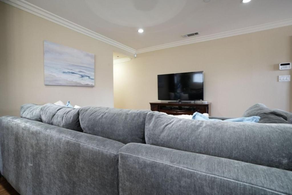 a gray couch in a living room with a tv at Comfy Pool Home,1/4 mile Walk To Disneyland in Anaheim