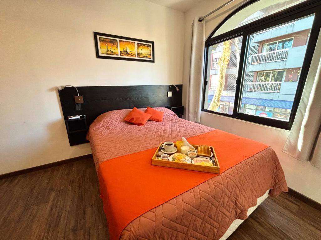 a hotel room with a bed with a tray of food on it at Hotel Los Pinos in Colonia del Sacramento