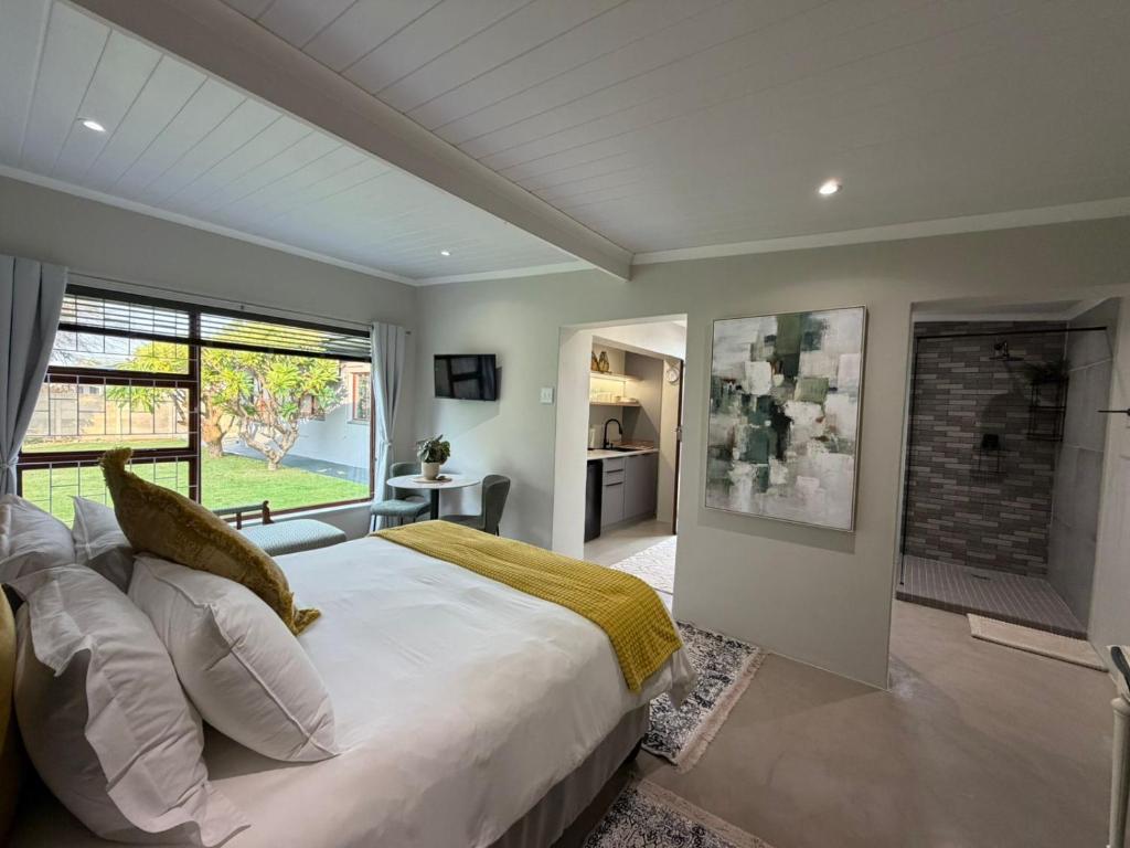a bedroom with a large bed and a large window at McCrae's Garden Suite in Malmesbury