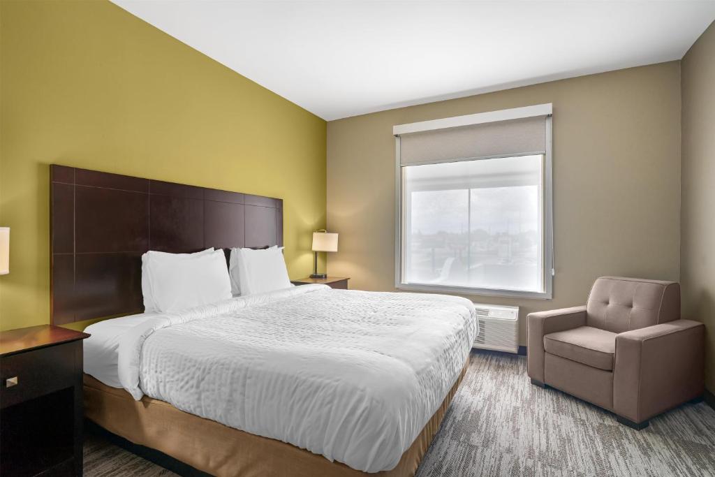 a bedroom with a bed and a chair and a window at Best Western Plus Chalmette Hotel in Chalmette