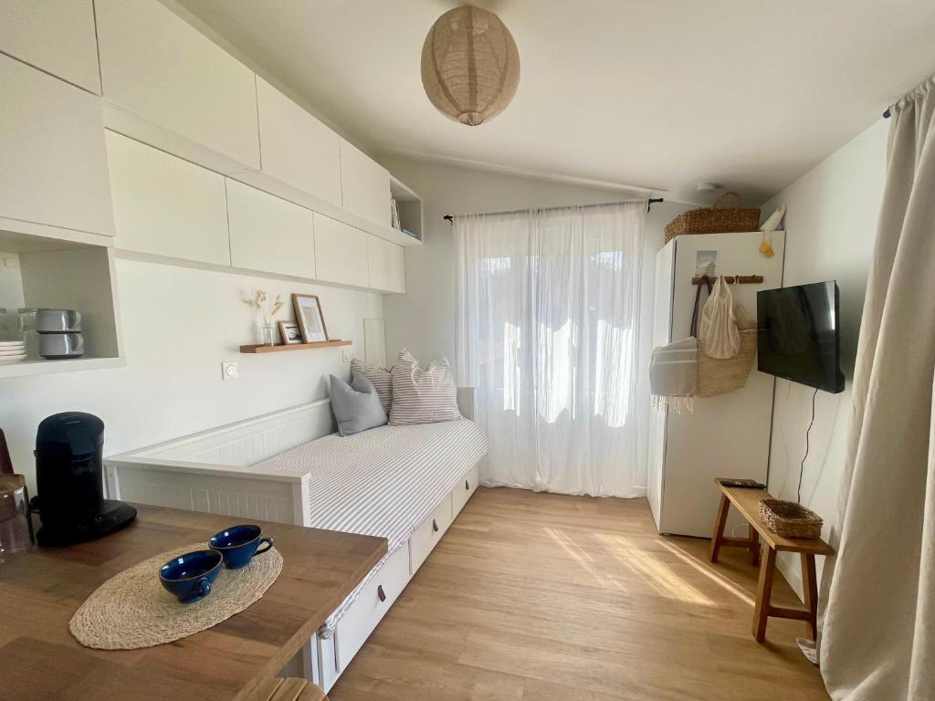 a white living room with a couch and a tv at Studio Le Petit Sablé in Concarneau
