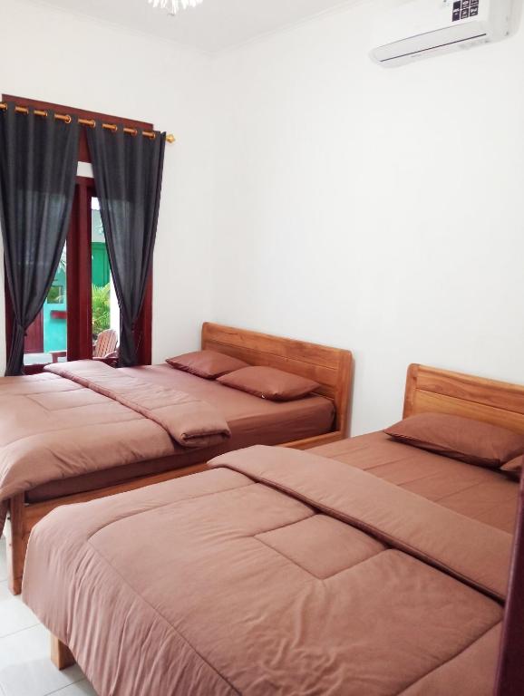 a room with three beds and a window at Sarwi Endah Beach Cottage in Tepus