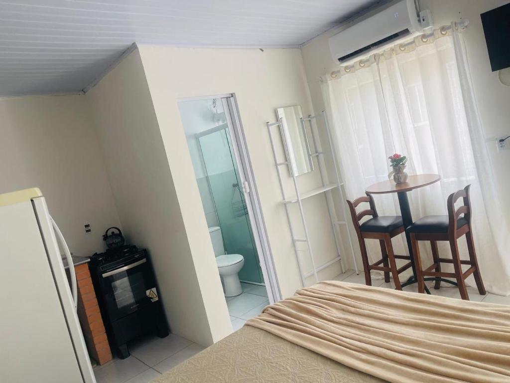 a bedroom with a bed and a table and chairs at Pousada Coral in Osório