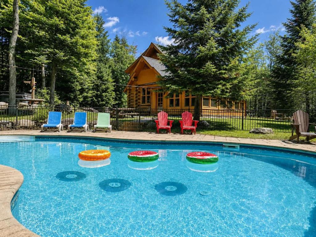 a swimming pool with chairs and a log cabin at Blue Bear Spa sauna private pool lake access in Wentworth