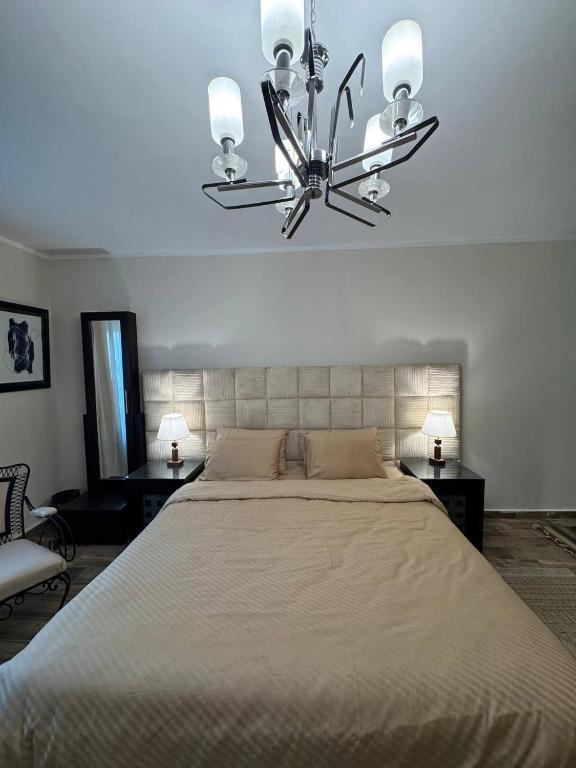 a bedroom with a large bed and a chandelier at Compound Canarya - 3 Bedroom Apartment in 6th Of October