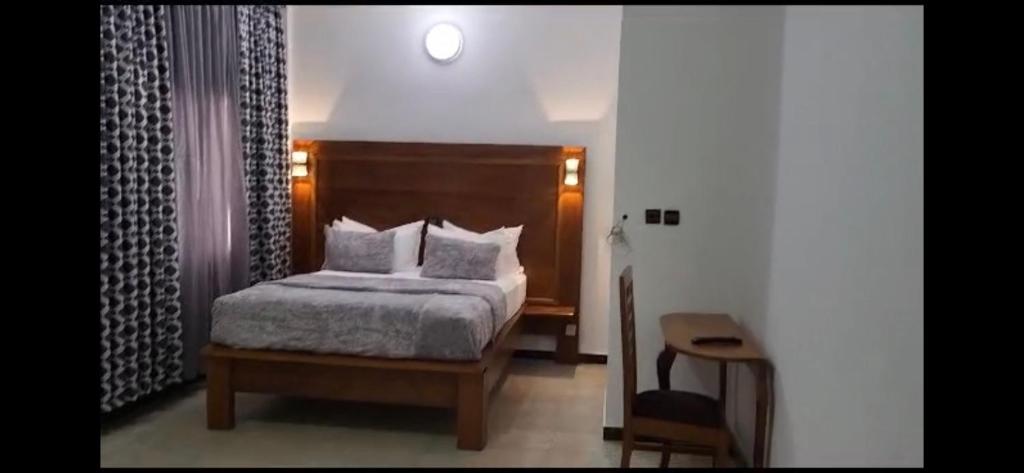 ein Schlafzimmer mit einem Bett mit weißen Laken und Kissen in der Unterkunft Jad Hotel Dschang in Dschang