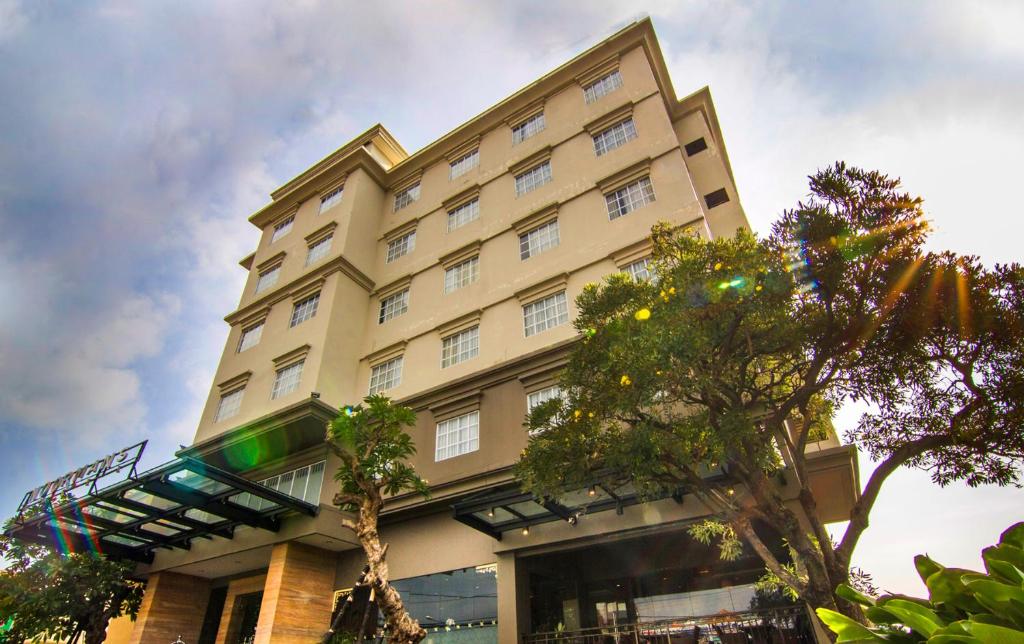 a large building with trees in front of it at Noormans Hotel Semarang in Semarang