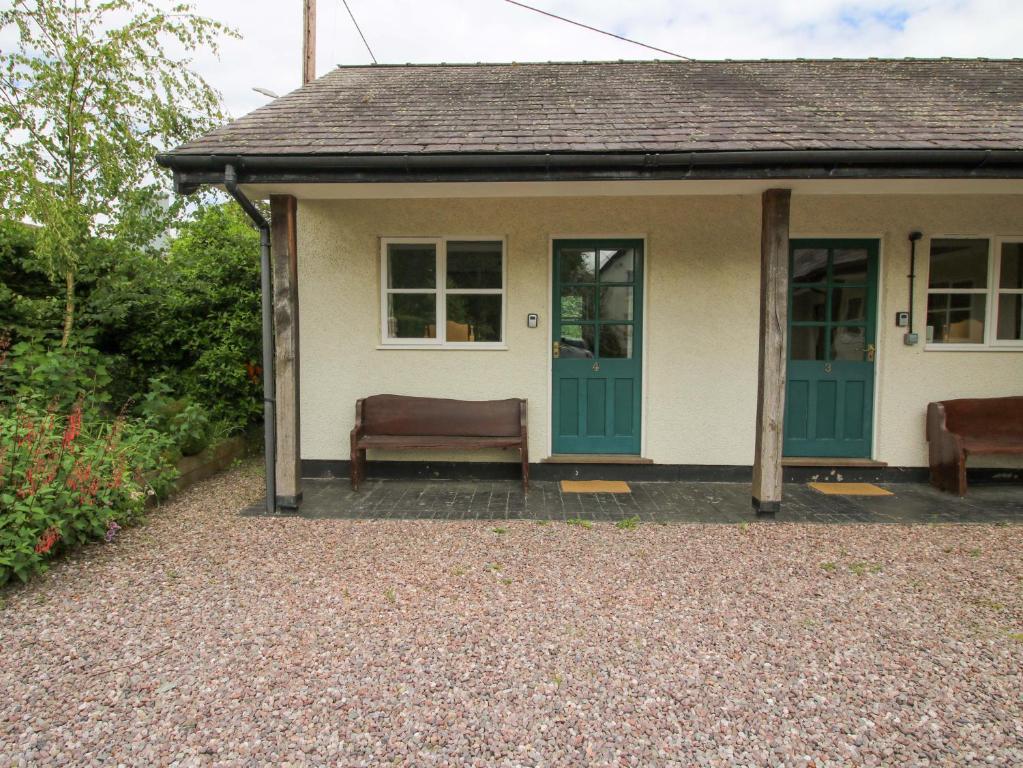 a small house with a green door and two chairs at Apartment 4 in North Lydbury