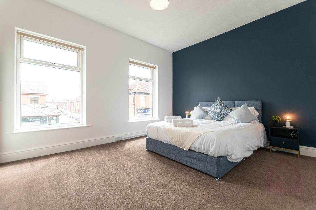 a bedroom with a large bed and two windows at Gordan Villas in Leigh