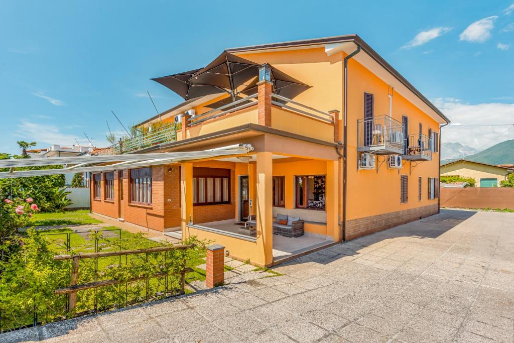 an orange house with a balcony and a yard at Hotel Sole in Marina di Massa
