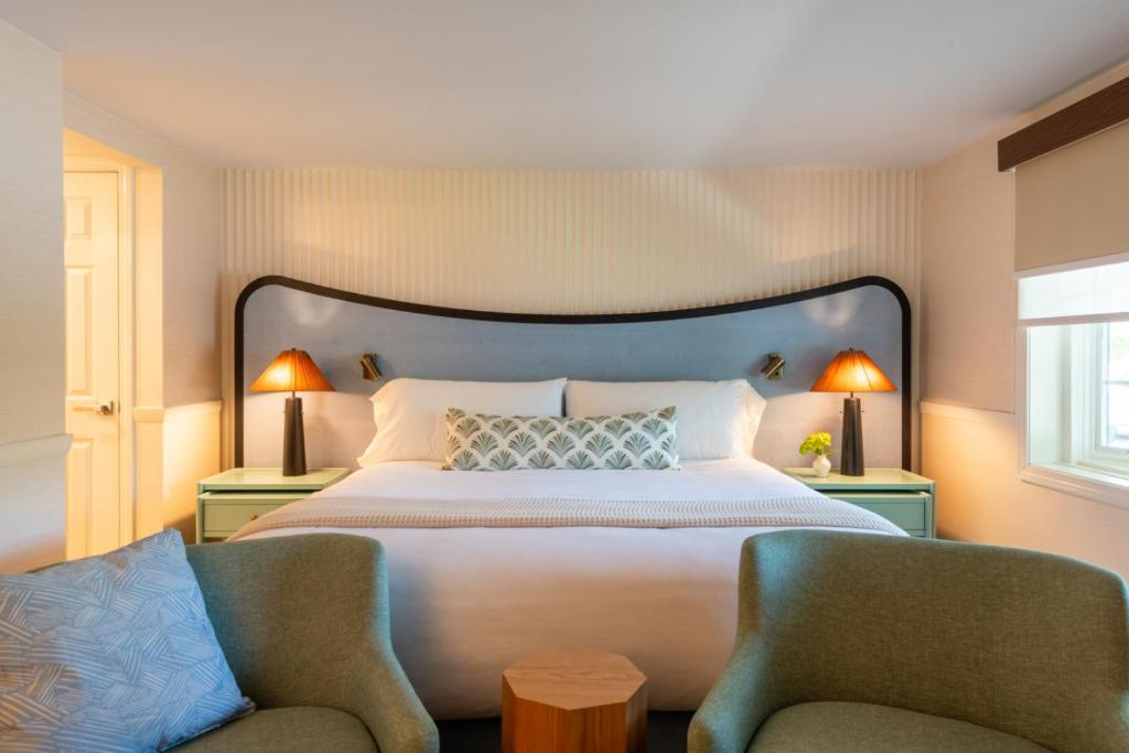 a bedroom with a large bed and two chairs at The Meadowmere Resort in Ogunquit
