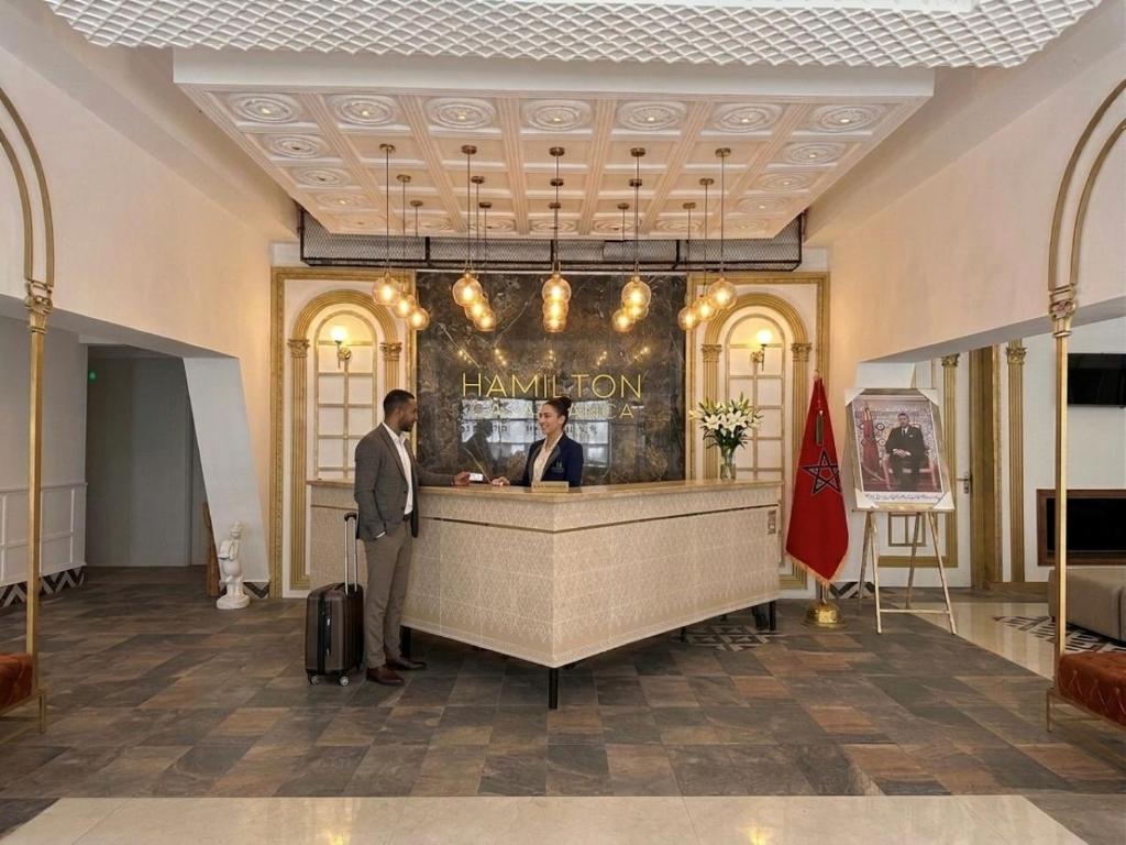 two people standing at a counter in a lobby at Hamilton Suites & Appart in Casablanca