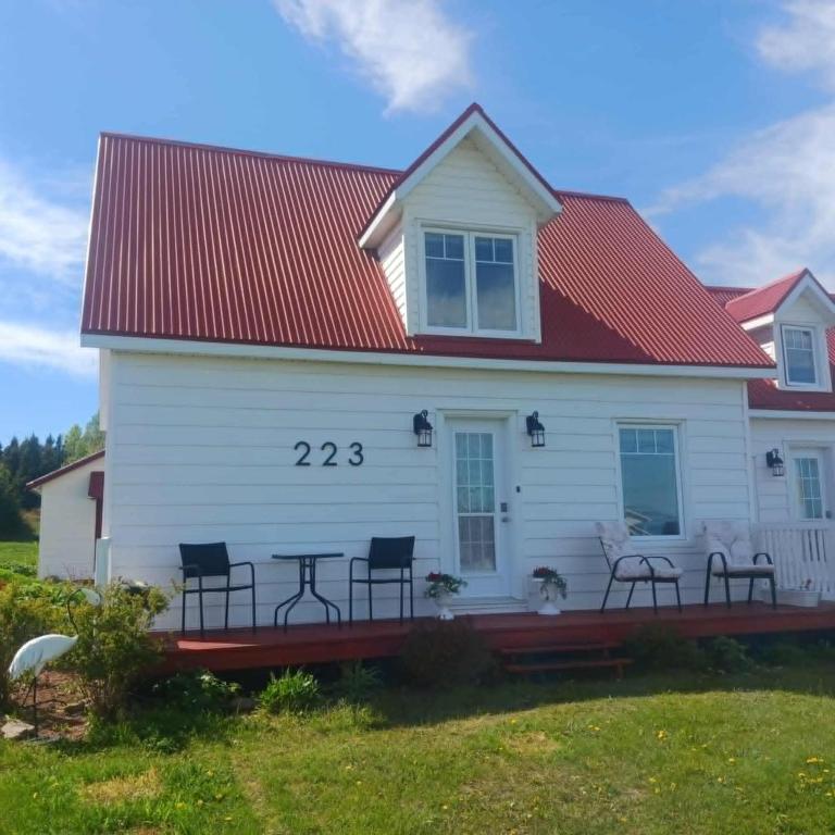 a white house with a red roof with chairs and a table at Le nid marin in Gascons
