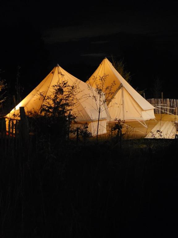 two large white tents are lit up at night at Tente Lima in Ambillou-Château