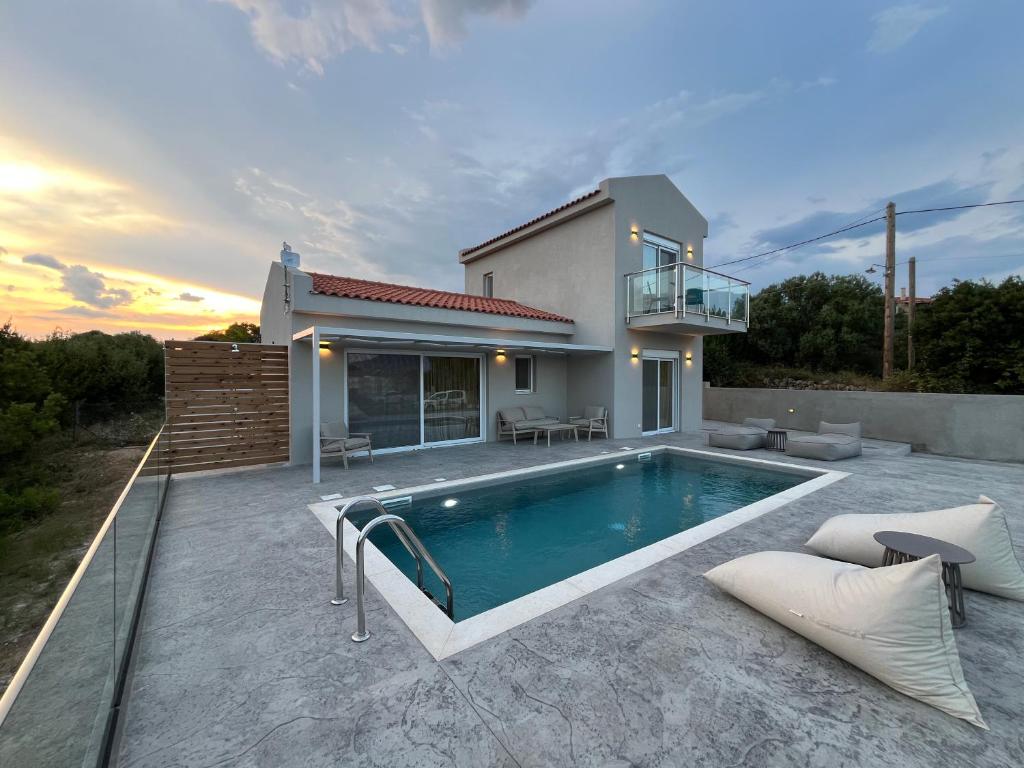 a villa with a swimming pool in front of a house at Zefy's Scenic Oasis in Pesádha
