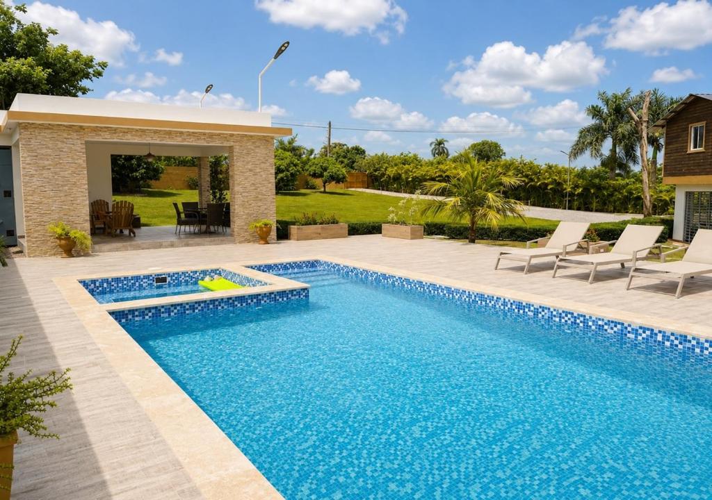 a swimming pool in a yard with chairs and a house at Villa la Santa, piscina infinita - Jacuzzi in Higuey