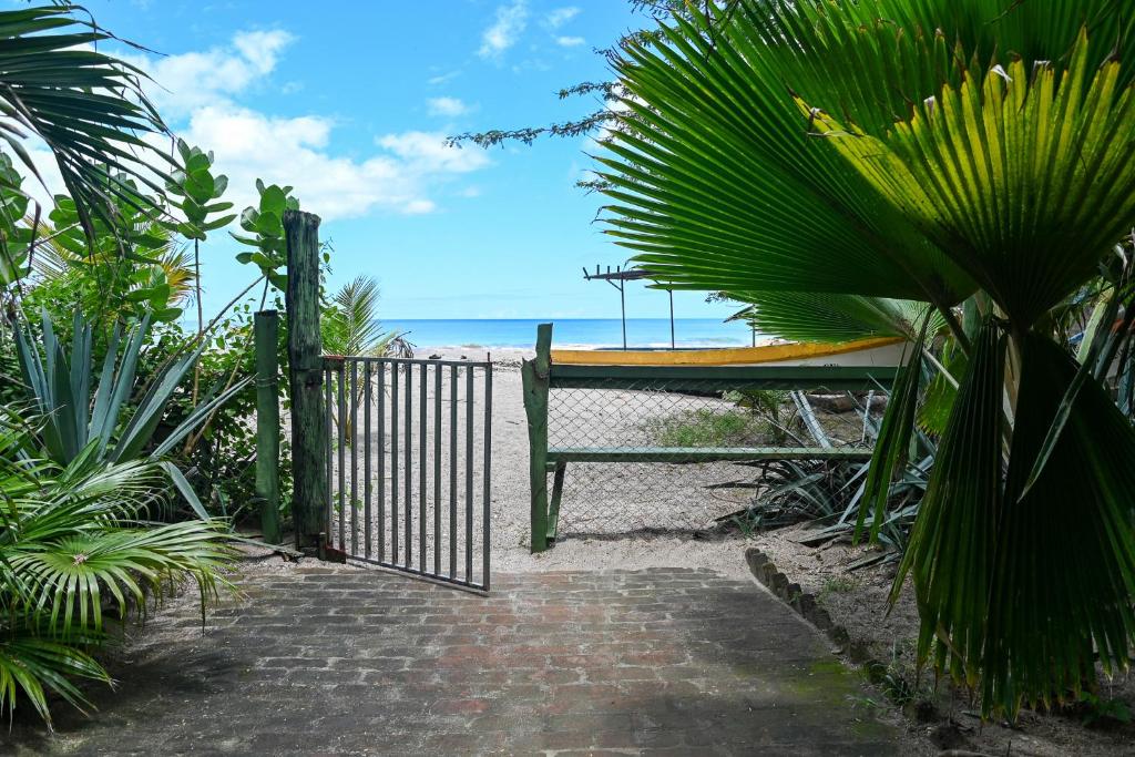 a wooden gate with a surfboard on the beach at Beach-Front Bungalow in El Gigante