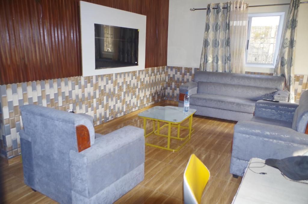a living room with two couches and a tv at Grand Studio à 200 m de la plage de Kribi Clim - Wi-Fi in Kribi