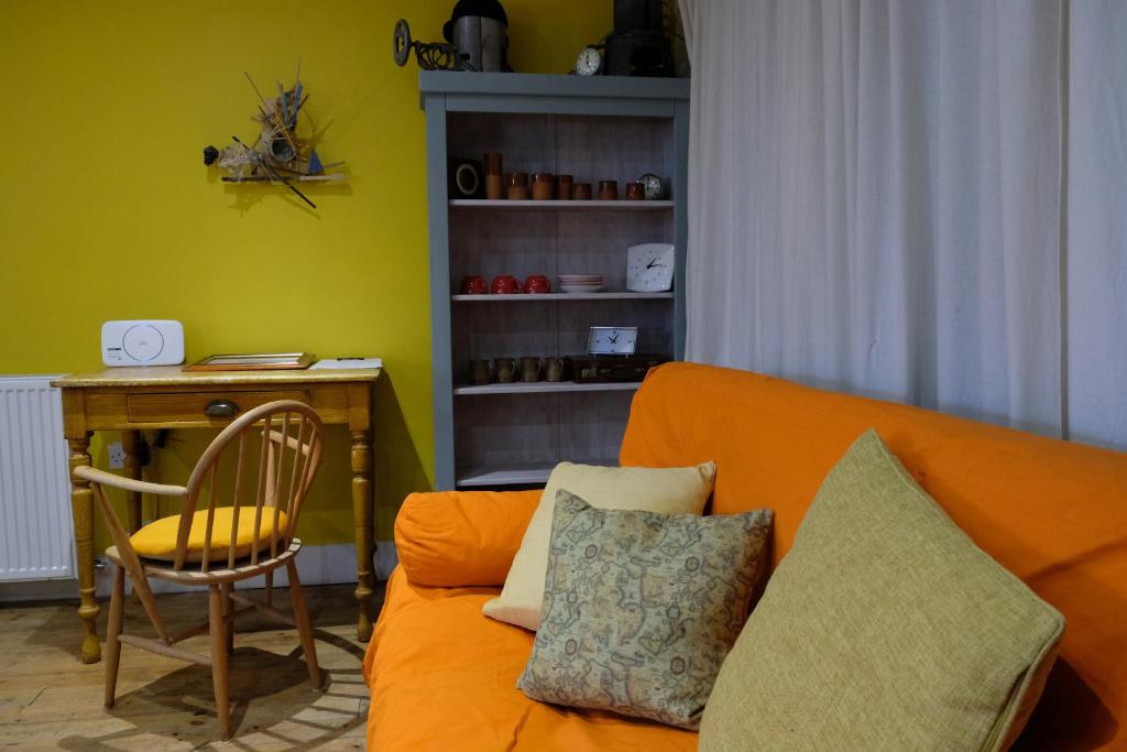 a living room with an orange couch and a desk at The Little Hatbox in Newburgh