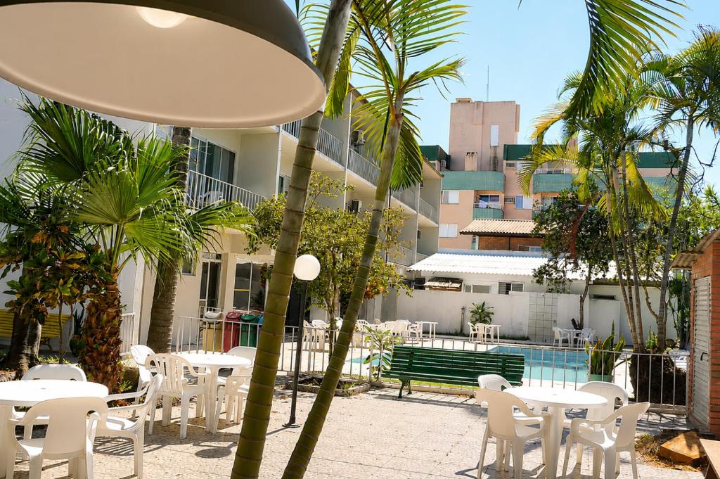 a patio with white tables and chairs and a building at HANNA Marina's Palace Hotel in Florianópolis