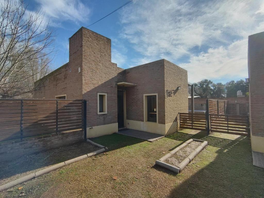 a brick building with a fence in front of it at Las Arecas in Carmen de Areco