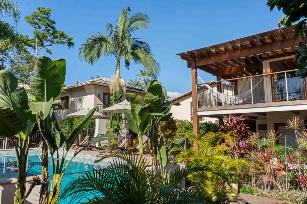 a house with a swimming pool and palm trees at Odoyá Casa Hotel in Paraty