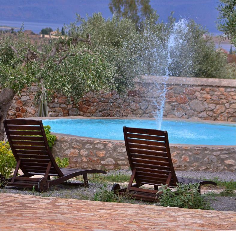 two rocking chairs sitting in front of a fountain at VILLA IN THE OLIVE TREES Galaxidi in Galaxidi